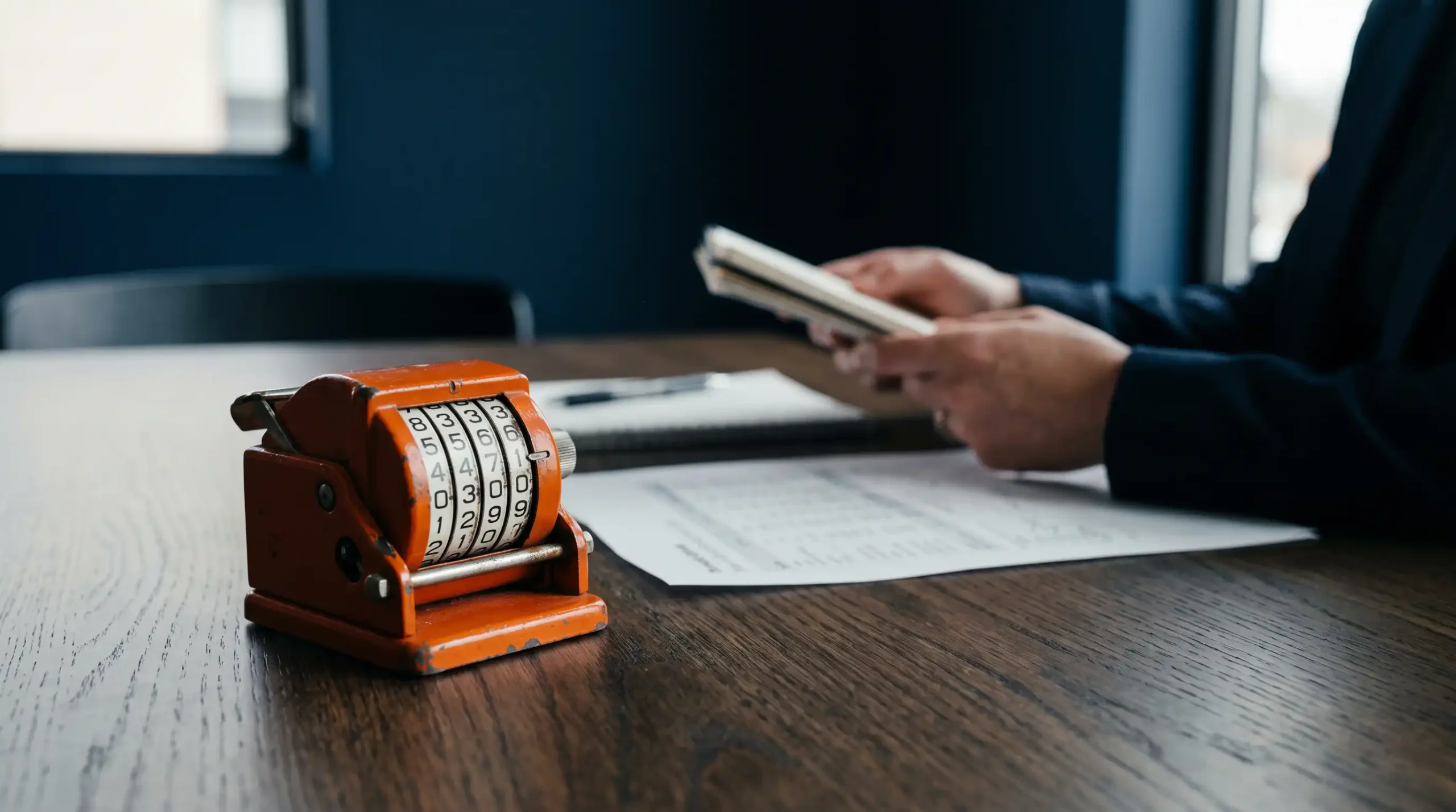 Profesional de marketing digital en su oficina analiza datos y anota una estrategia de puja (bidding strategy) con un contador vintage y gráficos de rendimiento sobre su escritorio.